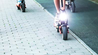 teenagers riding electric scooters with flashlights