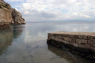 Stone pier and rocks on sea