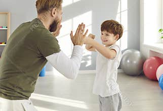 Family sport, father and young son boxing, fighting with fists, healthy happy fitness emotion