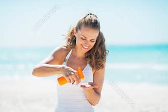 Happy woman on beach applying sun screen creme