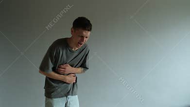Man suffering from stomach pain on gray background with copy space. Concept of health issue or food poisoning