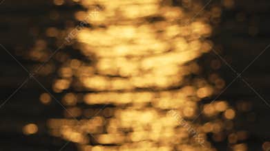 blurry, yellowish-orange sunset over water. The water appears to be rippling and the sky is filled with a warm, golden glow.