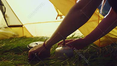 Woman mini portable gas stove, pot from tent. Solo camping, cooking outdoors. Ultralight gear for backpacking, self