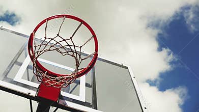 Basketball hoop with cage with clouds in background