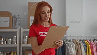 Woman volunteering indoors at donation center, reviewing clipboard amidst charity items, exuding joyful commitment to social