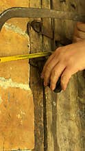 Man cutting padlock with hacksaw. Vintage wooden door in brick wall. Close-up. Vertical video