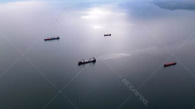 Aerial view of multiple cargo ships scattered across the calm open sea. The maritime scene highlights global trade