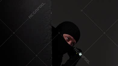 Masked Individual Partially Concealed in Shadows
