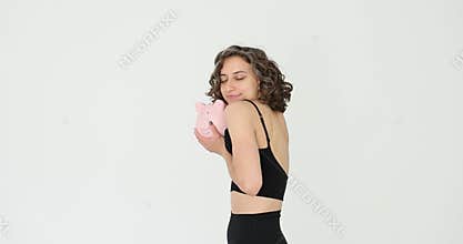 Young woman happily hugging piggy bank with care, demonstrating importance of saving money on white background