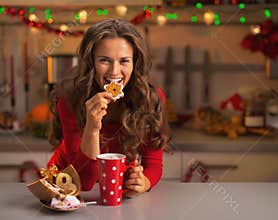 Happy young woman having eating christmas cookies in kitchen