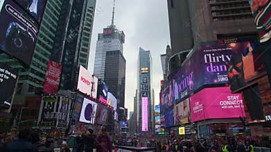 Glowing digital screens of advertisements on the skyscrapers in the Times Square and walking people