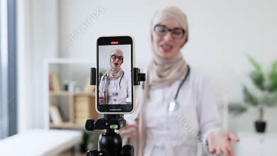 Muslim female doctor records online healing tutorial on smartphone