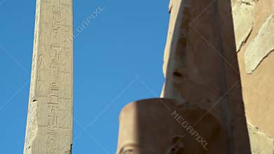 View of a tall obelisk in the ancient city of Karnax with an Egyptian statue of a pharaoh