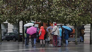 Group of tourists standing at Neuer Square (Neuer Platz), on a rainy day, in Klagenfurt, Austria