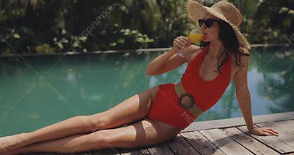 Stylish Woman Toasting by Poolside in Red Swimsuit and Hat