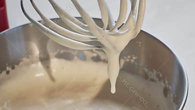 Beaten mass of eggs and sugar in a kitchen mixer. Preparation of sweet food.