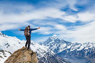 Hiker at the top of a rock with his hands raised enjoy sunny day
