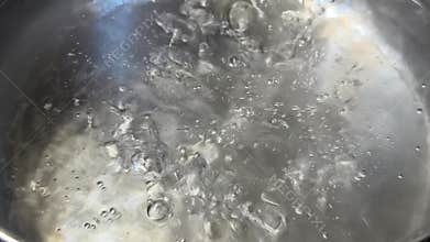 Closeups of bubbles forming and rising highlighting the dynamic transformation of water as it heats