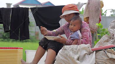 Mother sitting top of garbage bag feeding baby in slums