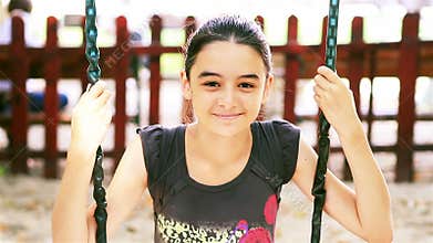Teenage girl on swing smiling at camera