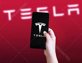 Close up of Electric car manufecturing company Tesla on the Smartphone Screen in hand, concept illustrative editorial background