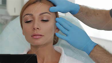 Cosmetologist skillfully stretches the skin over the client&#x27;s brow