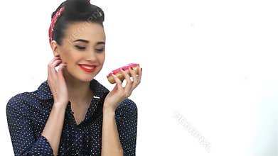 Charming fifties pin-up girl playfully holding a cookie