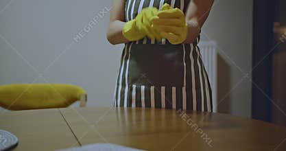 Woman in Yellow Gloves Prepares to Clean Dining Room Table. House Cleaning, Chore Time, and Cleaning Service Concept.