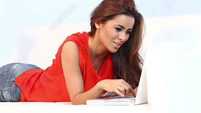 Pretty brunnette lying on sofa and working on computer
