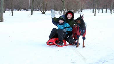 Woman, dog and kid on sledge posing for photographer