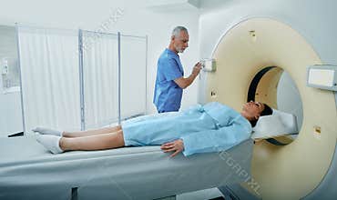 CT scan technologist overlooking a patient in CT scanner during settings on Computed Tomography scanner