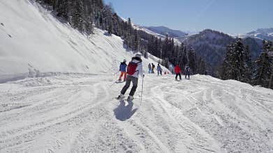 Skiers skillfully carving down maintained mountain pistes