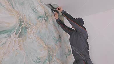 Trimming excess paper. Trimming wallpaper in the corners of a room after wallpapering.