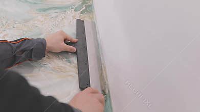 Trimming wallpaper in the corners of a room after wallpapering. Trimming excess paper.