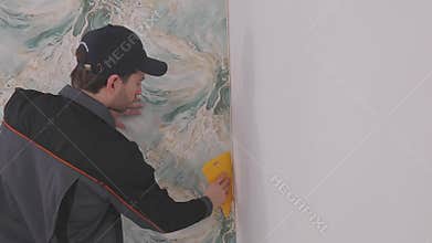 Trimming wallpaper in the corners of a room after wallpapering. Trimming excess paper.