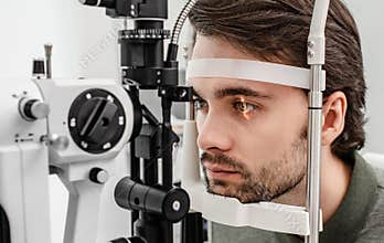 Handsome man getting an eye exam at ophthalmology clinic. Checking retina of a male eye close-up