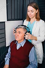 audiologist an auditory examination, for an elderly man using special equipment