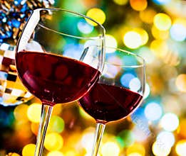 Red wine glasses against colorful bokeh lights and sparkling disco ball background