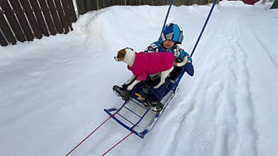 A woman carries her son and dog on a sled.