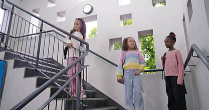Three African girls entering from left into school stairs climbing gesturing moving with backpacks