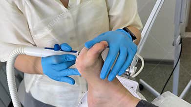 Professional pedicure procedure performed by a technician in blue gloves providing careful foot and nail care for a
