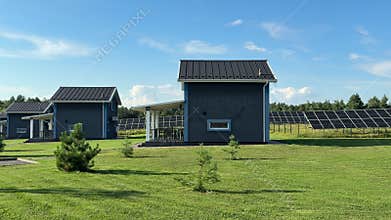 Modern holiday cabins with rooftop solar panels surrounded by green grass under a blue sky