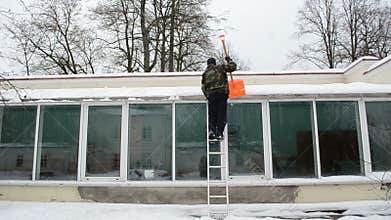 Man ladder orange shovel tool clean snow greenhouse roof winter