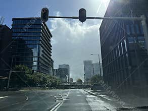 Empty urban intersection between modern glass office towers, wet asphalt