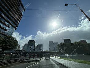 Sunny urban street view with modern office towers, overhead tram wires