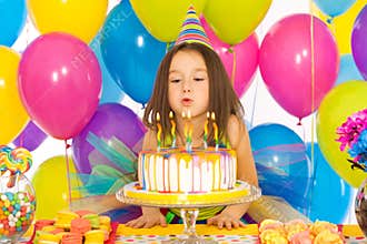 Little girl blowing candles on birthday cake