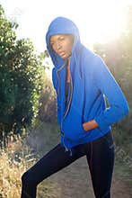 Female fitness model posing with blue sweatshirt outdoors