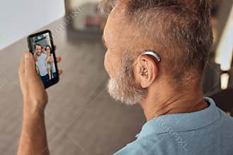 Senior man with hearing aid behind the ear communicates with his family
