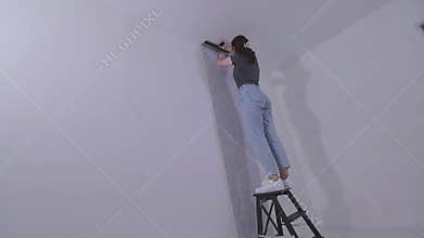 Trimming wallpaper in the corners of a room after wallpapering. Trimming excess paper.