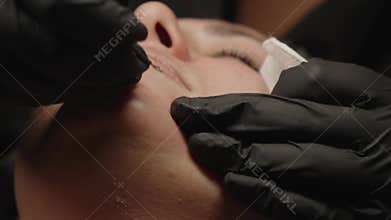 Professional cosmetologist performing manual facial extraction